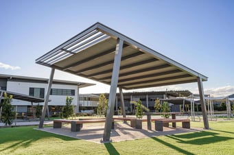 Red Gum shade shelter with large span design and minimal posts, providing flexible outdoor seating area in a public park